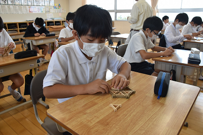 三角形に加工された木片を組み合わせて円を作る男子児童の写真