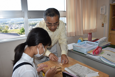 着席した女子児童と傍に立つメガネ姿の男性が話している写真