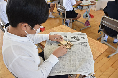 新聞紙の上で作業する男子児童の写真