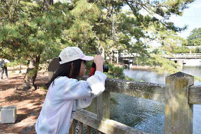 橋の手すりにカメラを置き、撮影する女の子の写真