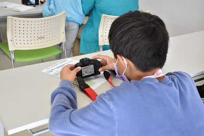 長机に腕を置き、カメラを見る少年の写真