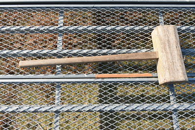 鉄網の足場に置かれた木製の小槌の写真