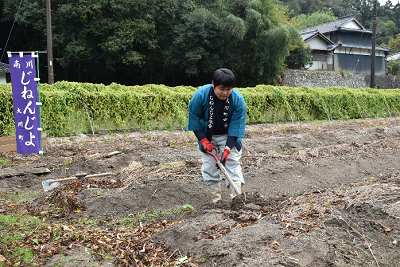 法被を着た男性が畑で土を掘っている写真