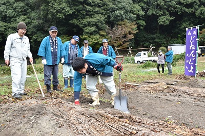法被を着た男性が土を探っている写真