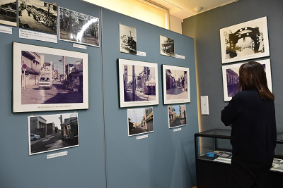 展示パネルに飾られている写真を見る女性の写真