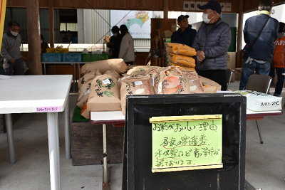 紙袋に入った米が机の上に積み上げられて販売されている写真