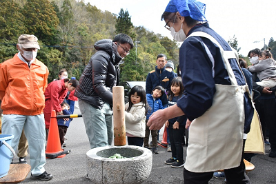 臼の上で杵を一緒に持ち上げる親子の写真