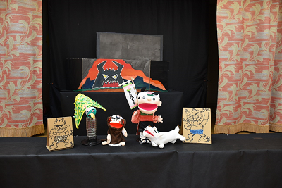 黒い台に置かれた桃模様の鉢巻きをした少年とイヌ、サル、キジの人形の写真