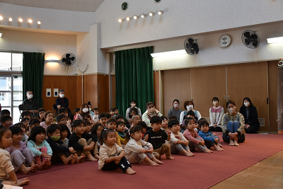 体育座りして前を向く子供たちの写真