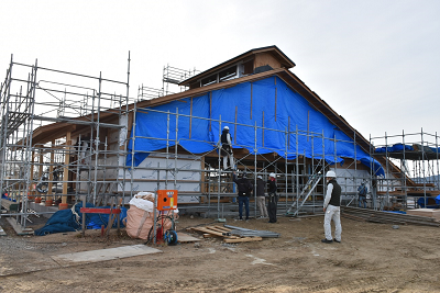 建設中の建物にブルーシートや足場が設置されている写真