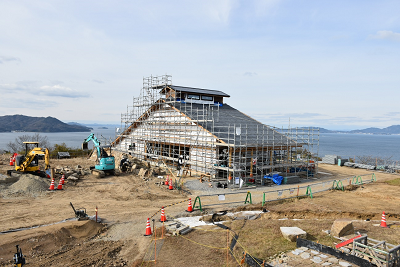 水面の近くで建築途中の建物の周りに足場が組まれている写真