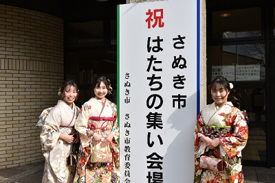 看板の左右に立つ振り袖姿の女性たちの写真