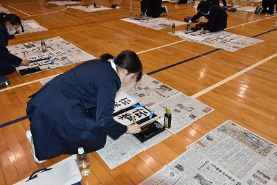 書初めで「伝統」を書いている児童の写真
