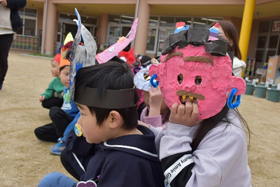 園児が手作りの赤い鬼のお面を被っている写真