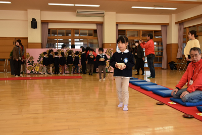 園児たちが列になって茶碗を運んでいる写真