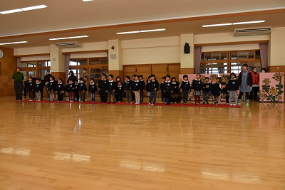 赤いカーペットの上で列になって並ぶ園児たちの写真