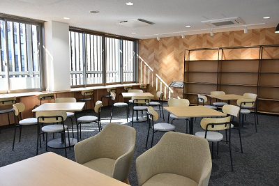 日差しの入る室内で正方形のテーブルに椅子が4脚で複数配置されている写真