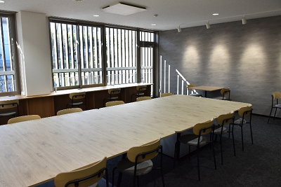 一つの大きなテーブルに複数の椅子が置かれた室内の写真