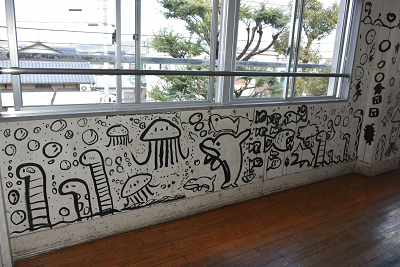 モノクロで海の生物がペイントされた校舎の壁の写真