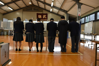 投票用紙に書き込みをする生徒たちの後ろ姿の写真