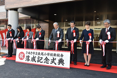 落成記念式典で大勢の人が同時にテープカットをする写真