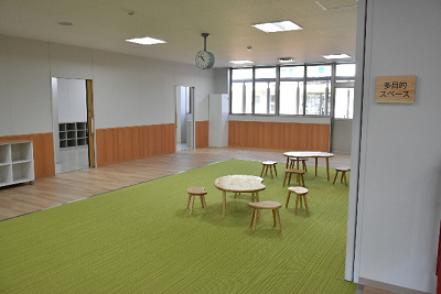 背の低い机と椅子、絨毯が敷いてある多目的スペースの写真