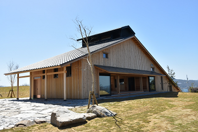 芝生の庭と石畳の小道が備わった切妻屋根の木造建築物の写真