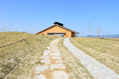 山脈を背景に建つ木造建築物へ続く石畳の小道の写真