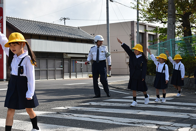 手を挙げて横断歩道を渡る児童の写真