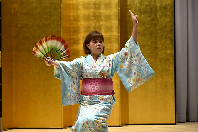 扇を持って踊る水色の着物を着た女性の写真