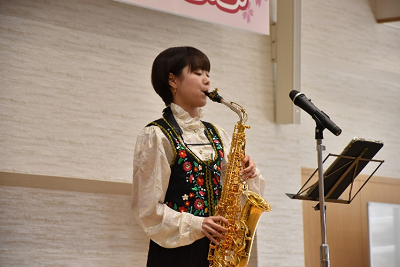 スタンドマイクの前でサックスを演奏する女性の写真