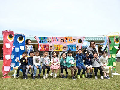 ベンチに一列に座る園児たちの両脇にこいのぼりが置かれた写真