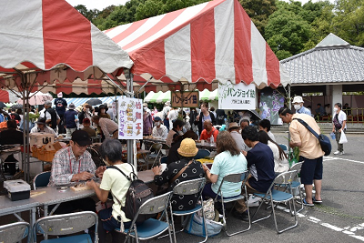 赤白の縞模様のテントでパイプ椅子に座る人々の写真