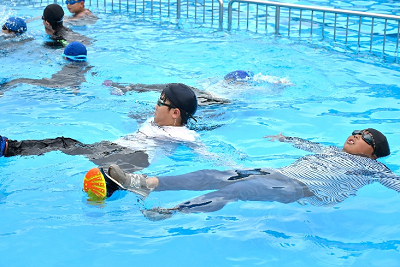 着衣で水面に浮く練習をする児童達の写真