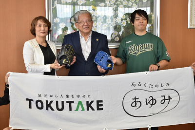 男女3人が2つの野球用グローブを持って並んでいる写真