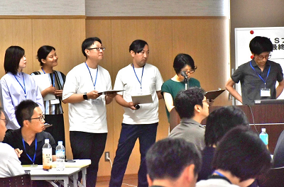 壇上で発表している男女6人の写真