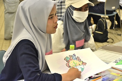 描いたイラストを見せながら話している女性の写真