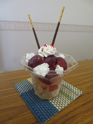 容器にぶどうや生クリーム、チョコのお菓子が盛り付けられた手作りパフェの写真