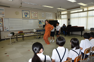 児童達の前でポーズを取っている男性の写真