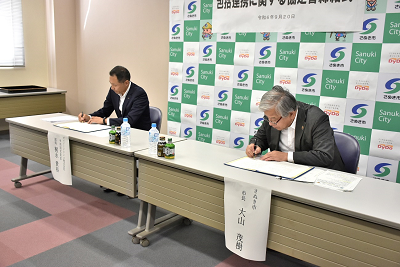 長机に置かれた書類に記入をしている男性2人の写真