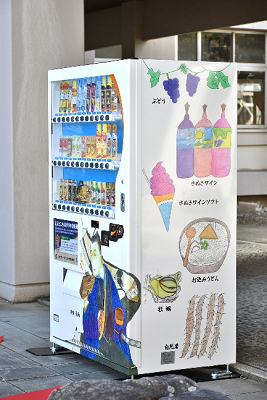 ぶどうやワインなどの特産物が自動販売機の側面に描かれている写真