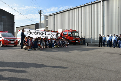 子供たちと保護者たちが並んで横断幕を持っている写真