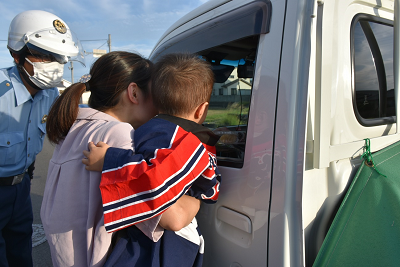 保護者が子供を抱えながらドライバーに声をかけている写真