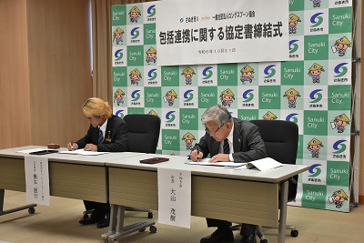 机に置かれた書類に書き込んでいる男性2人の写真