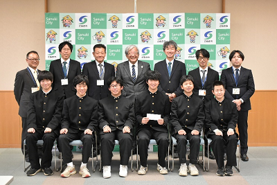 椅子に座って並ぶ人たちと、その後ろ上で立っていると大人達の写真