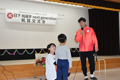 子供に向かって話すジャージ姿の人の写真