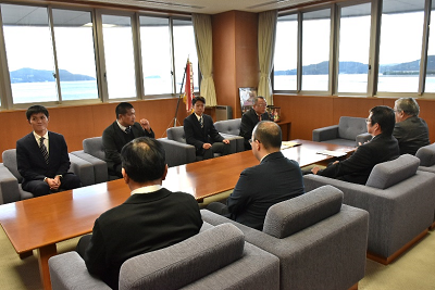 椅子に座っているスーツ姿の男性達と話している生徒達の写真