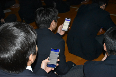 手に持ったスマホを見ている生徒達の写真