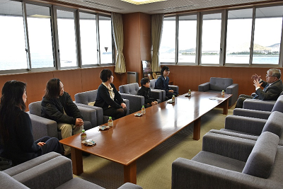 応接室で長机を挟んで向かい合って座る男性と児童の写真