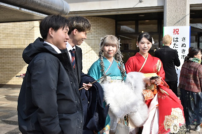 振り袖姿の女性2人とスーツ姿の男性2名が話している写真